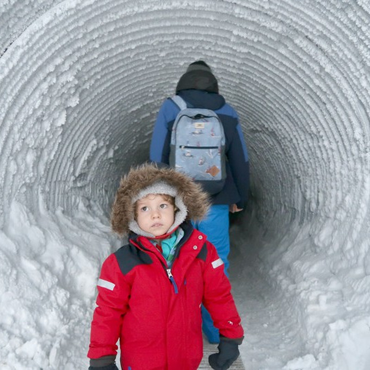 child and father walking inside a glacier