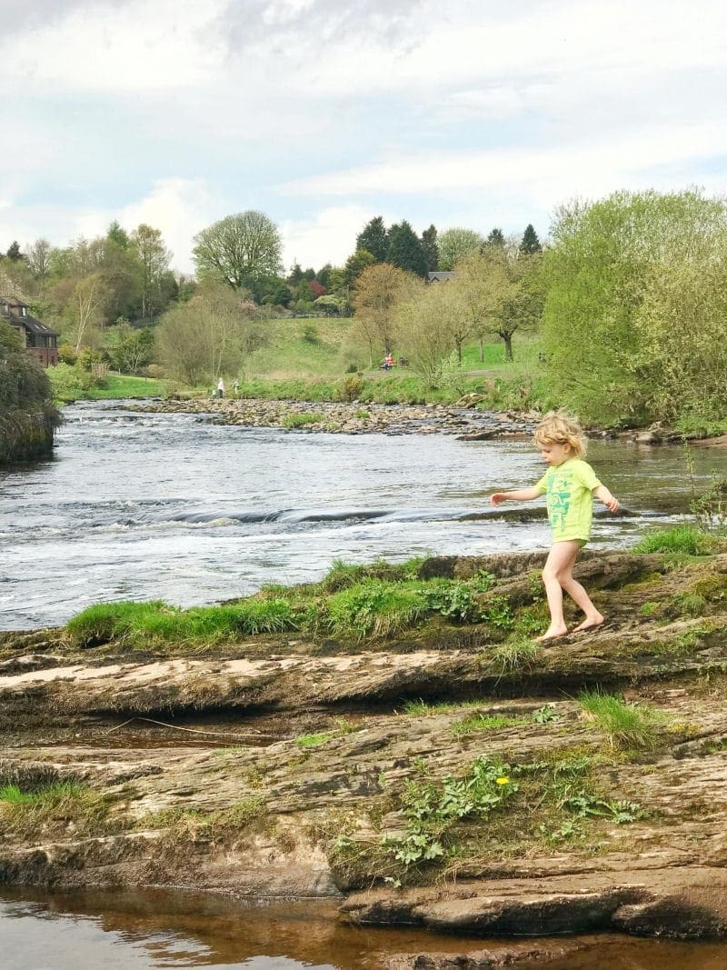 child running on rocks beside a river