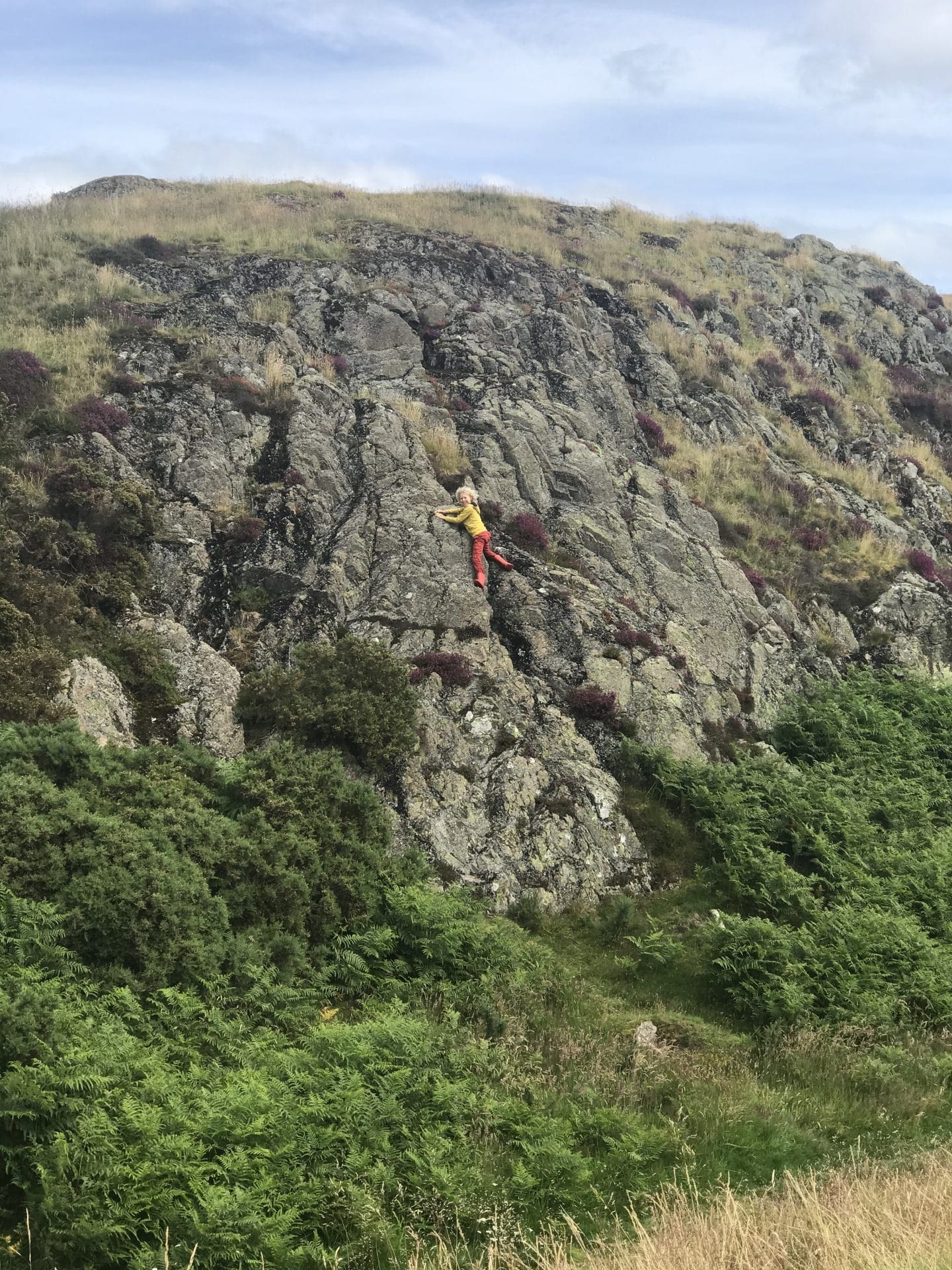 child climbing a rock cliff