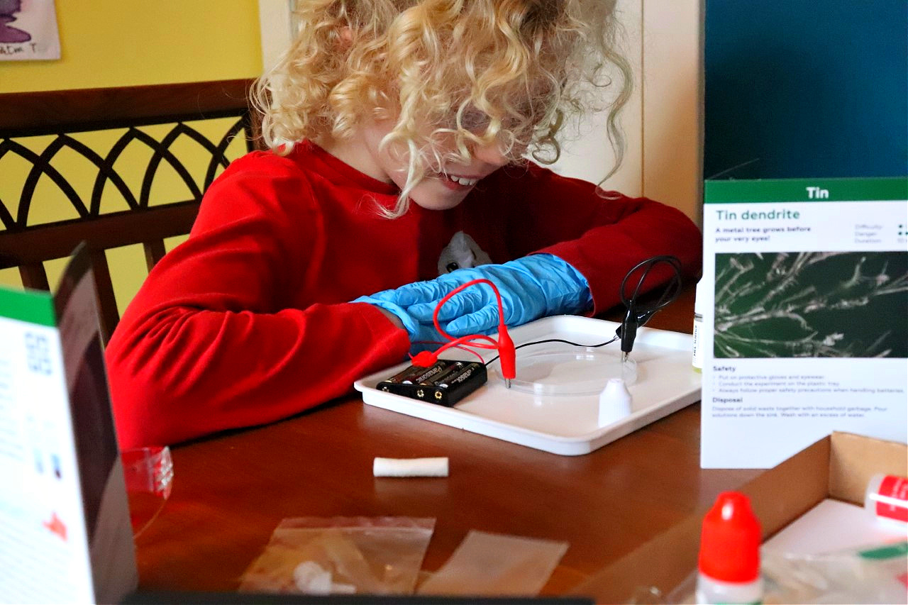 child performing a science experiment at kitchen table for home education