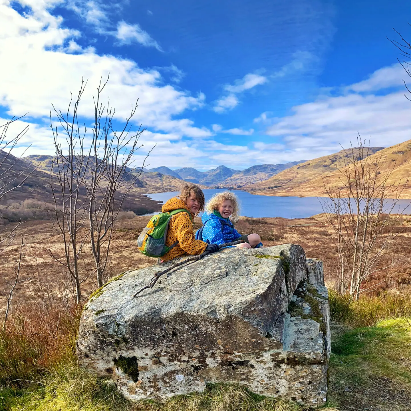 2 children sitting on a large rock overlooking loch Arklet
