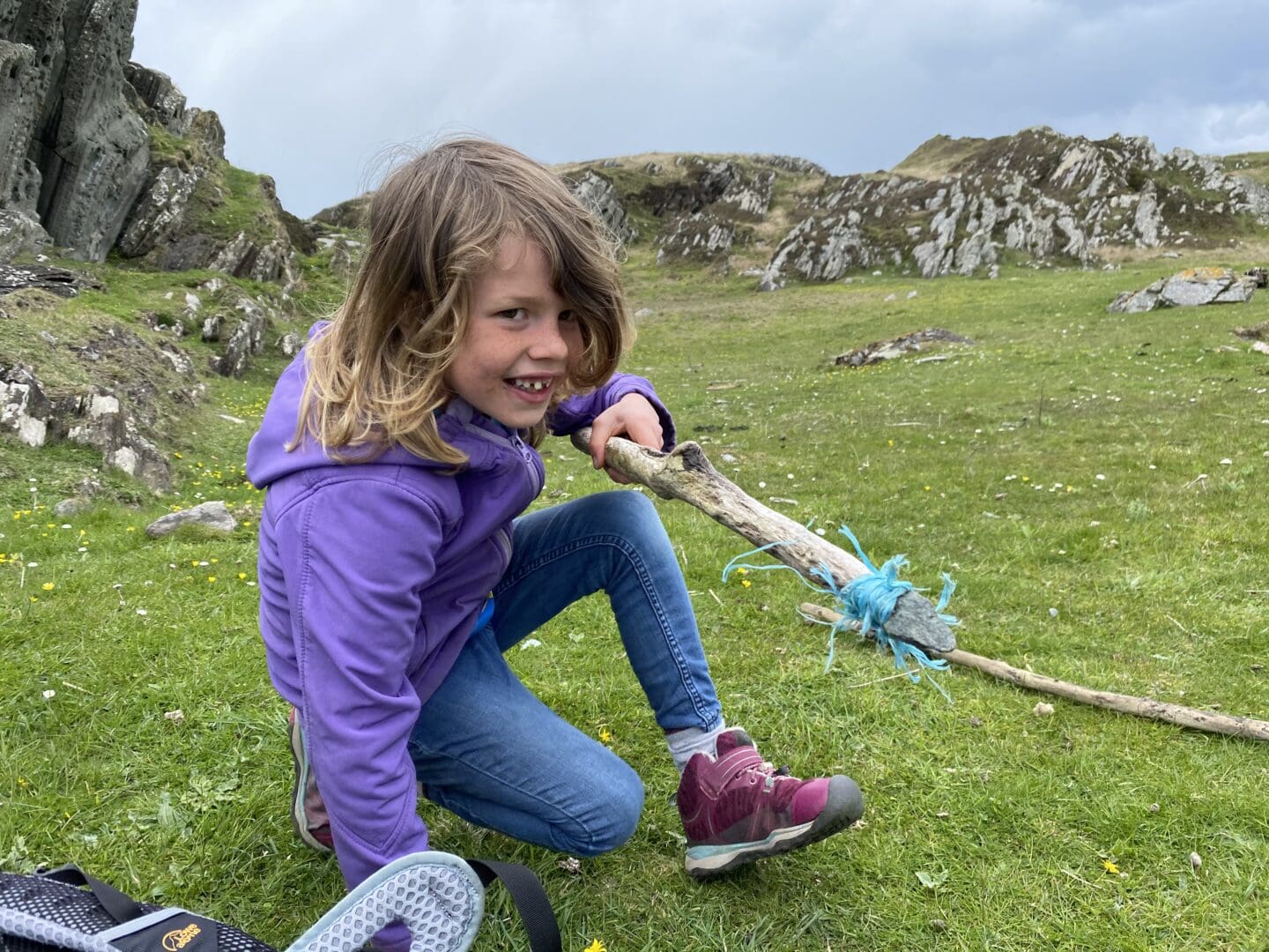 child with a wooden stick and piece of rock tied to it as a spear
