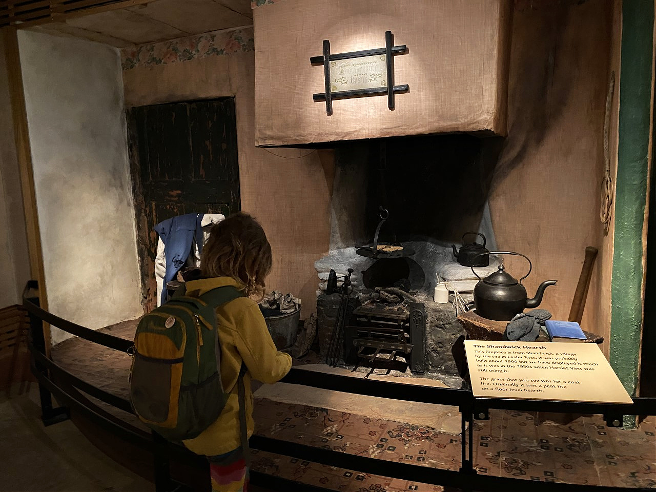 Child looking at a display of an old fireplace kitchen
