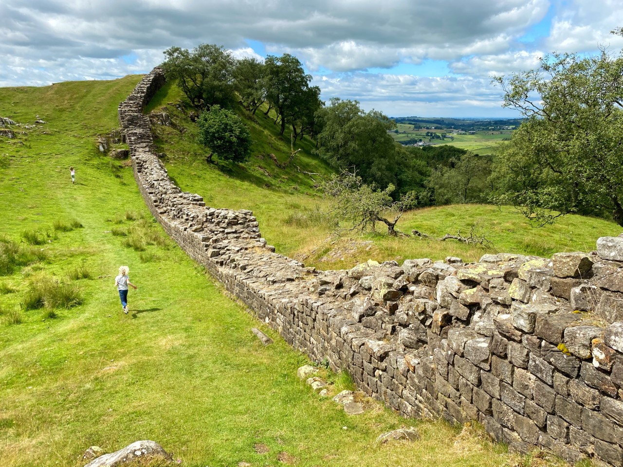 children running alongside a section of Hadrian's Wall
