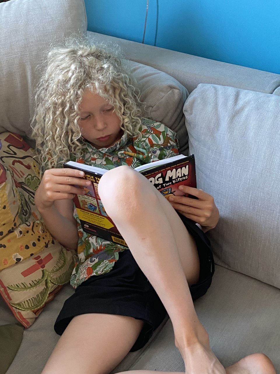 child reading Dogman book on sofa