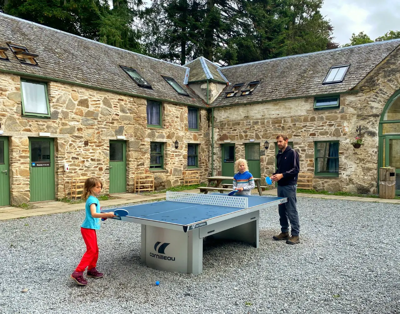 family playing table tennis outside old steading cottage