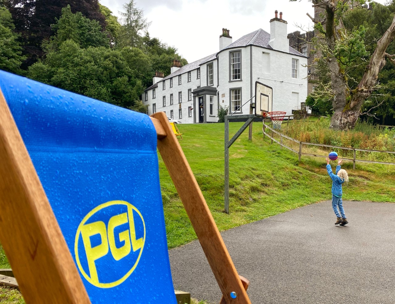 deck chair with PGL logo in front of Dalguise house with a child throwing a basketball