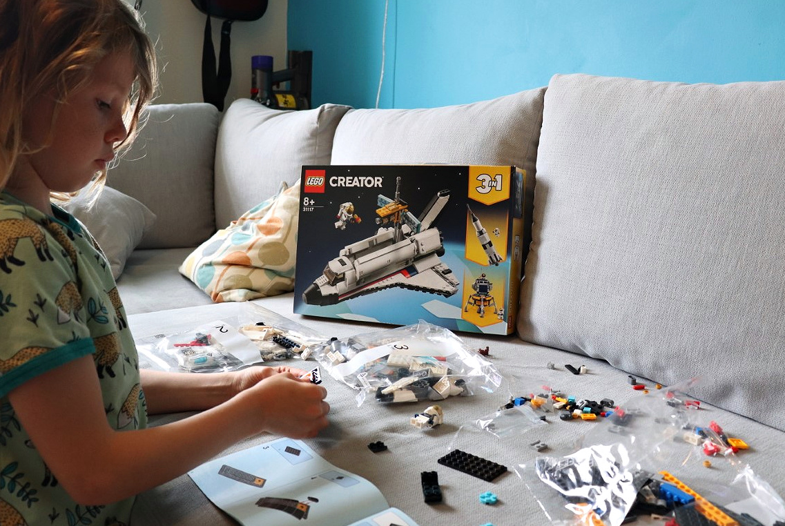 child building a lego space shuttle