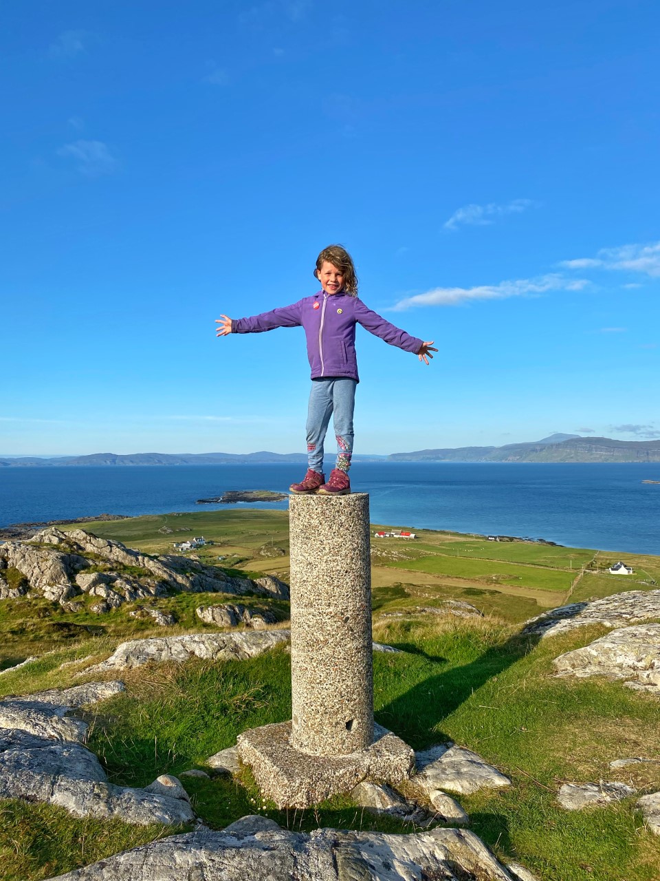 child standing on top of trig point on Dun I Iona