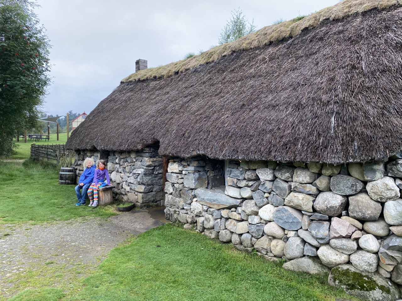 children outside reconstructed croft house