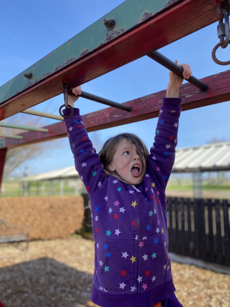 child swinging from monkey bars