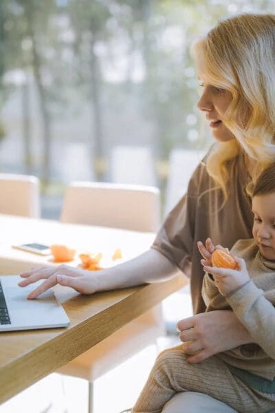Lady sitting with child on lap whilst using a laptop