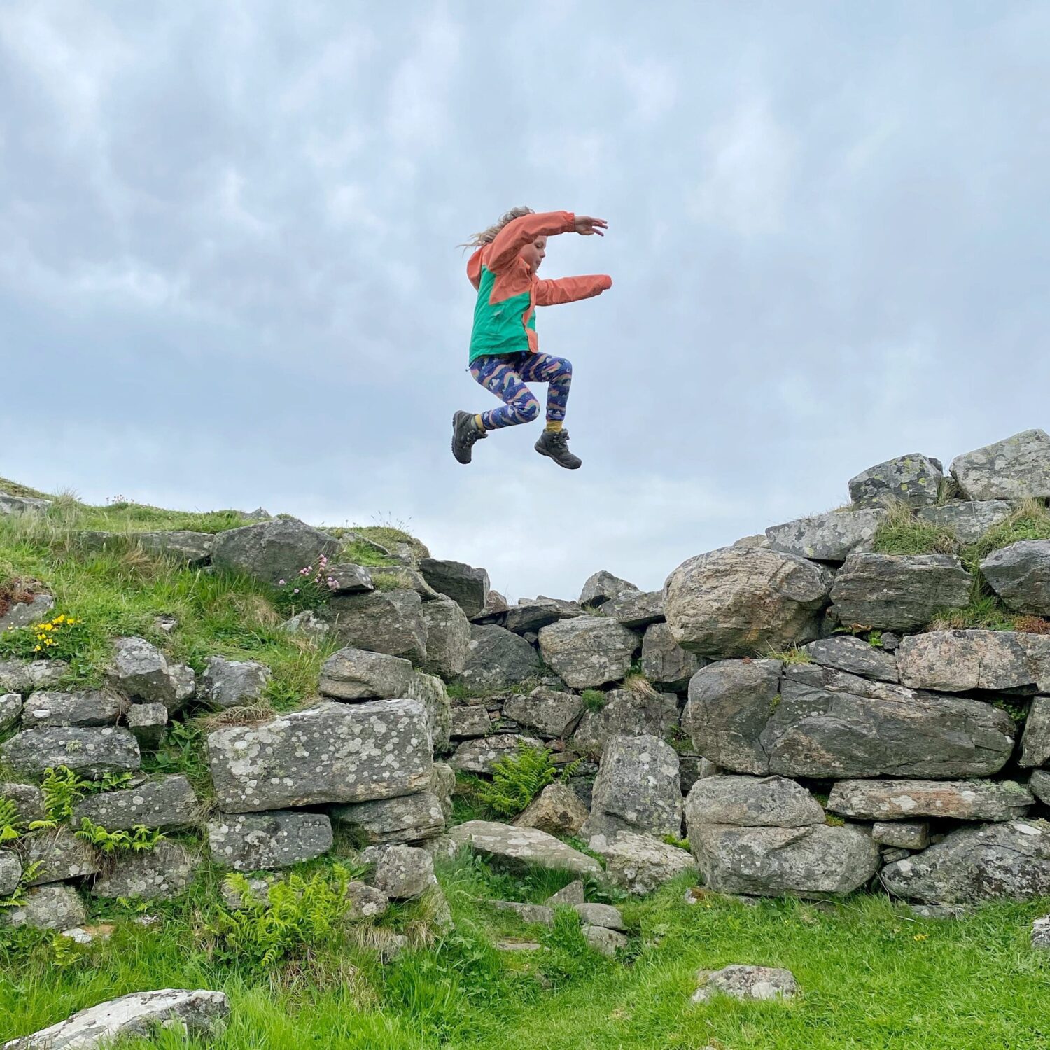 Child jumping over brooch wall