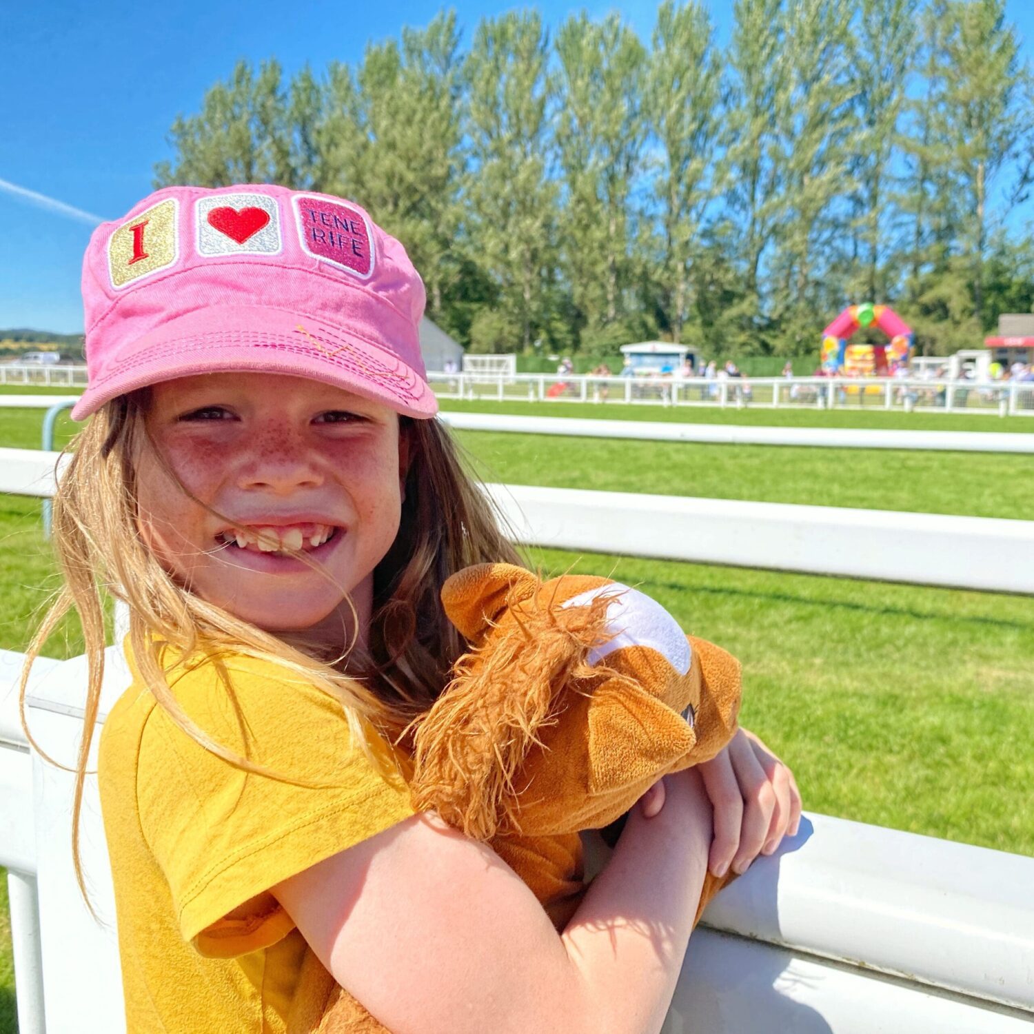 Child with stuffed horse toy watching the races