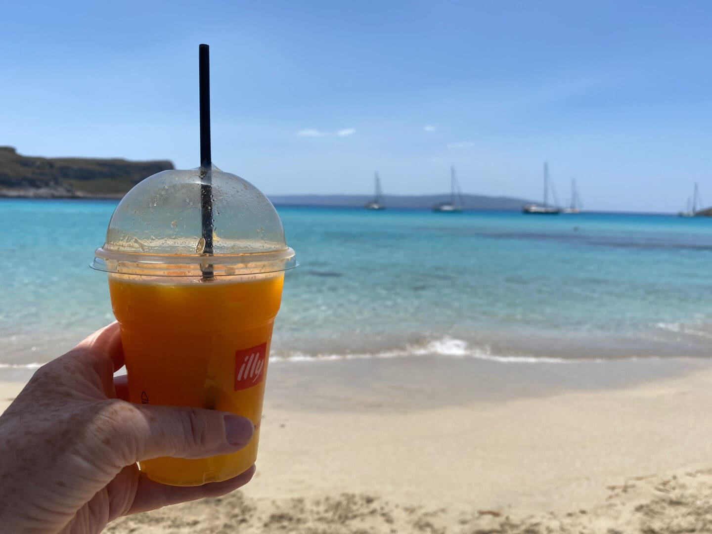 Little Simos beach with drink in front of blue sea and sail boats