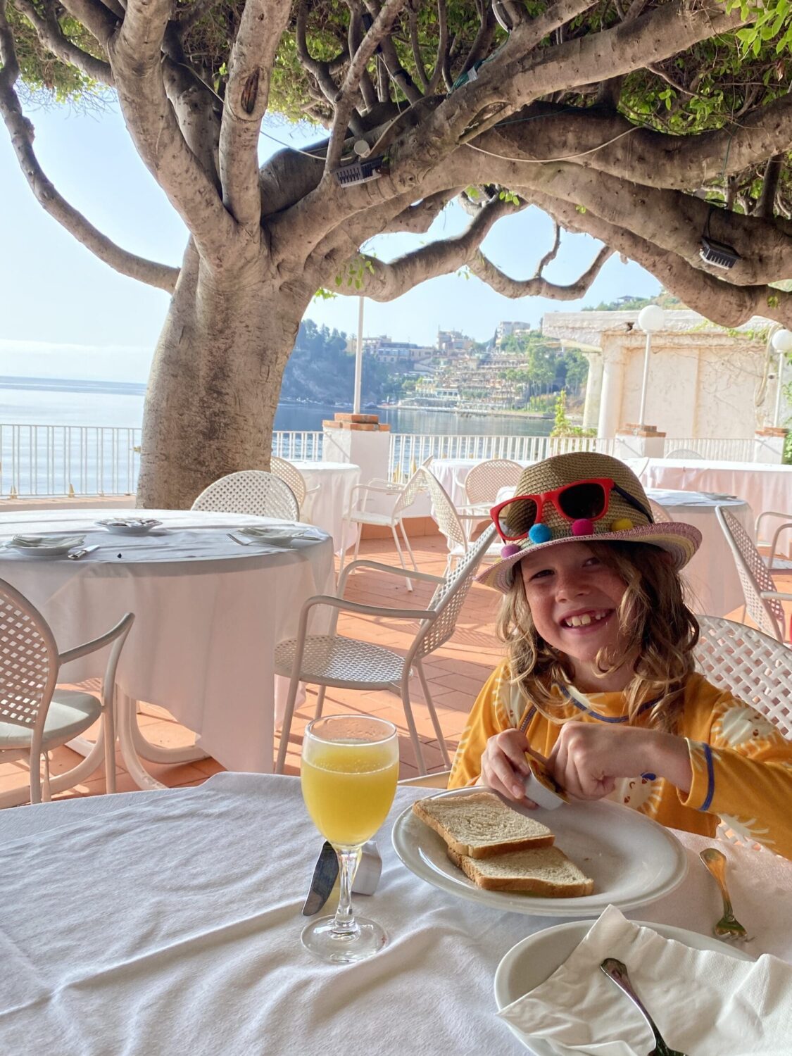 Child enjoying breakfast and juice at the beach Taormina