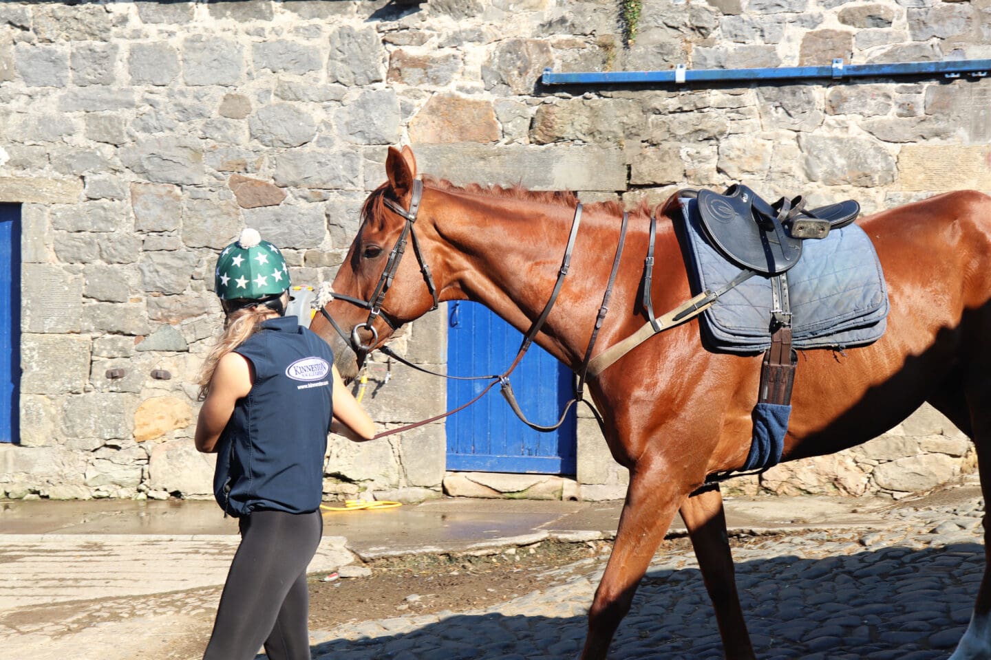 Trainer leading racehorse out of the stables