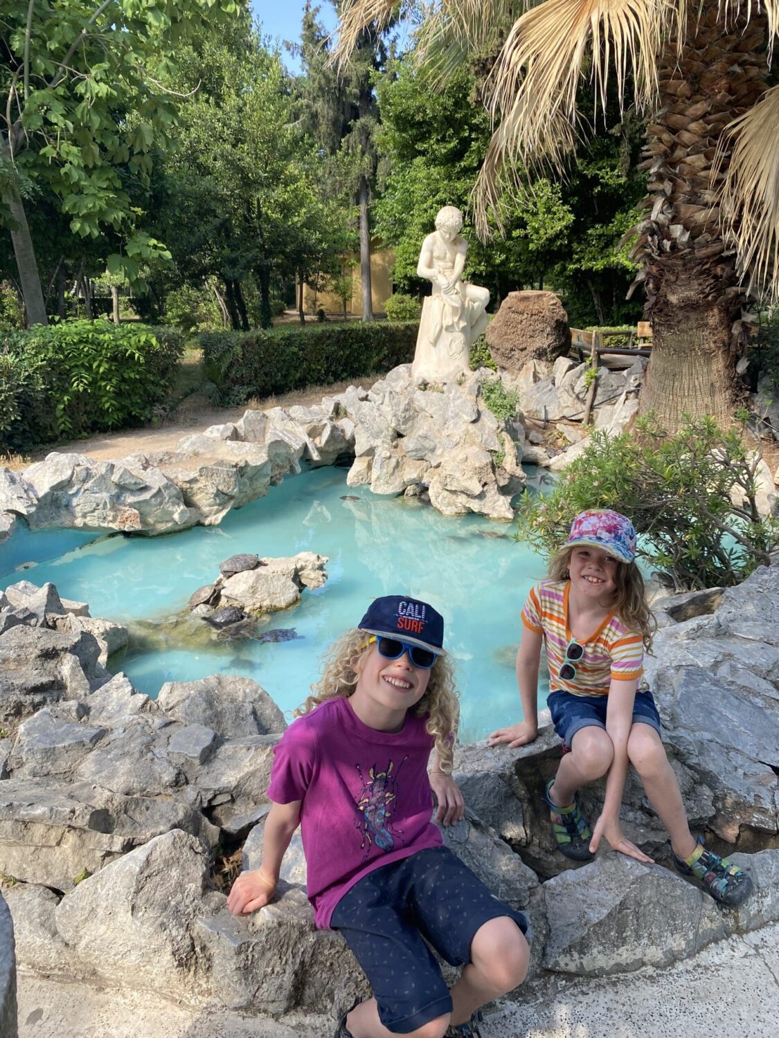 Children in front of blue pool fountain with turtles