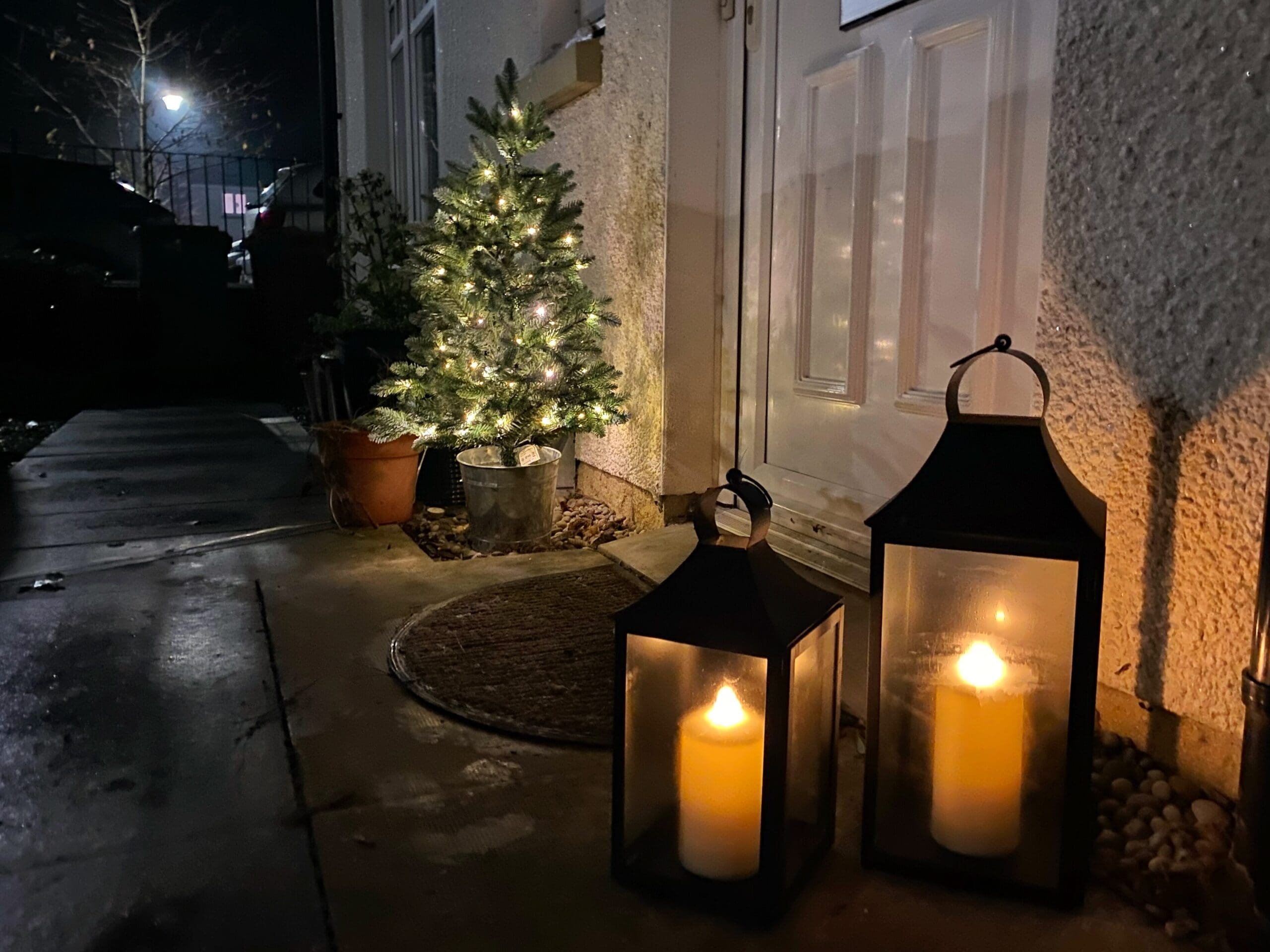 Battery powered lantern lights and Christmas tree outside a door