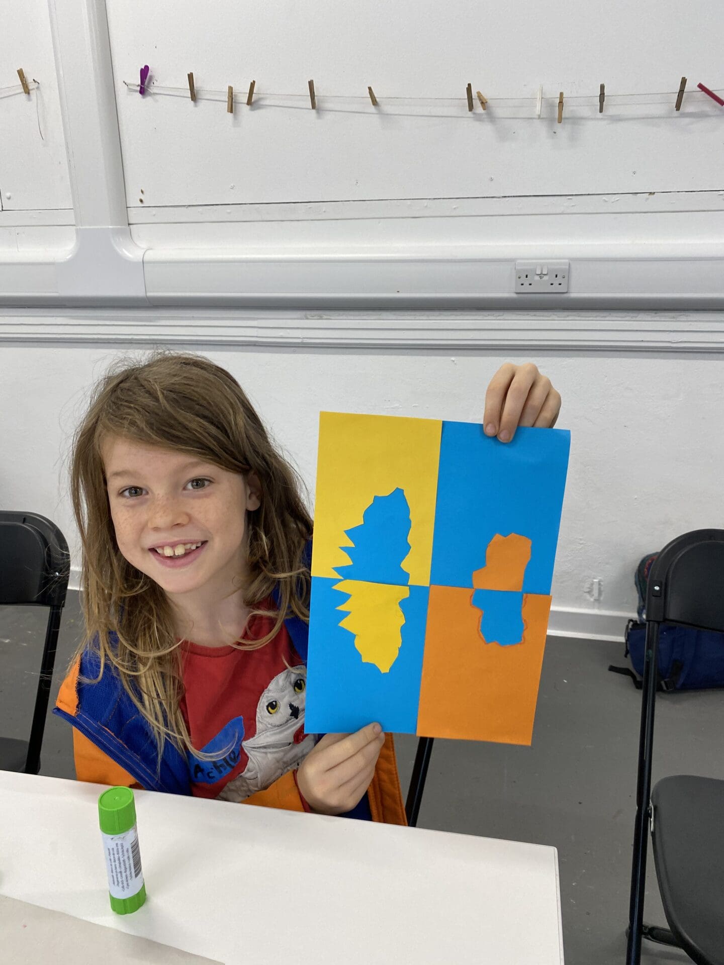 Child holding up art work for camera