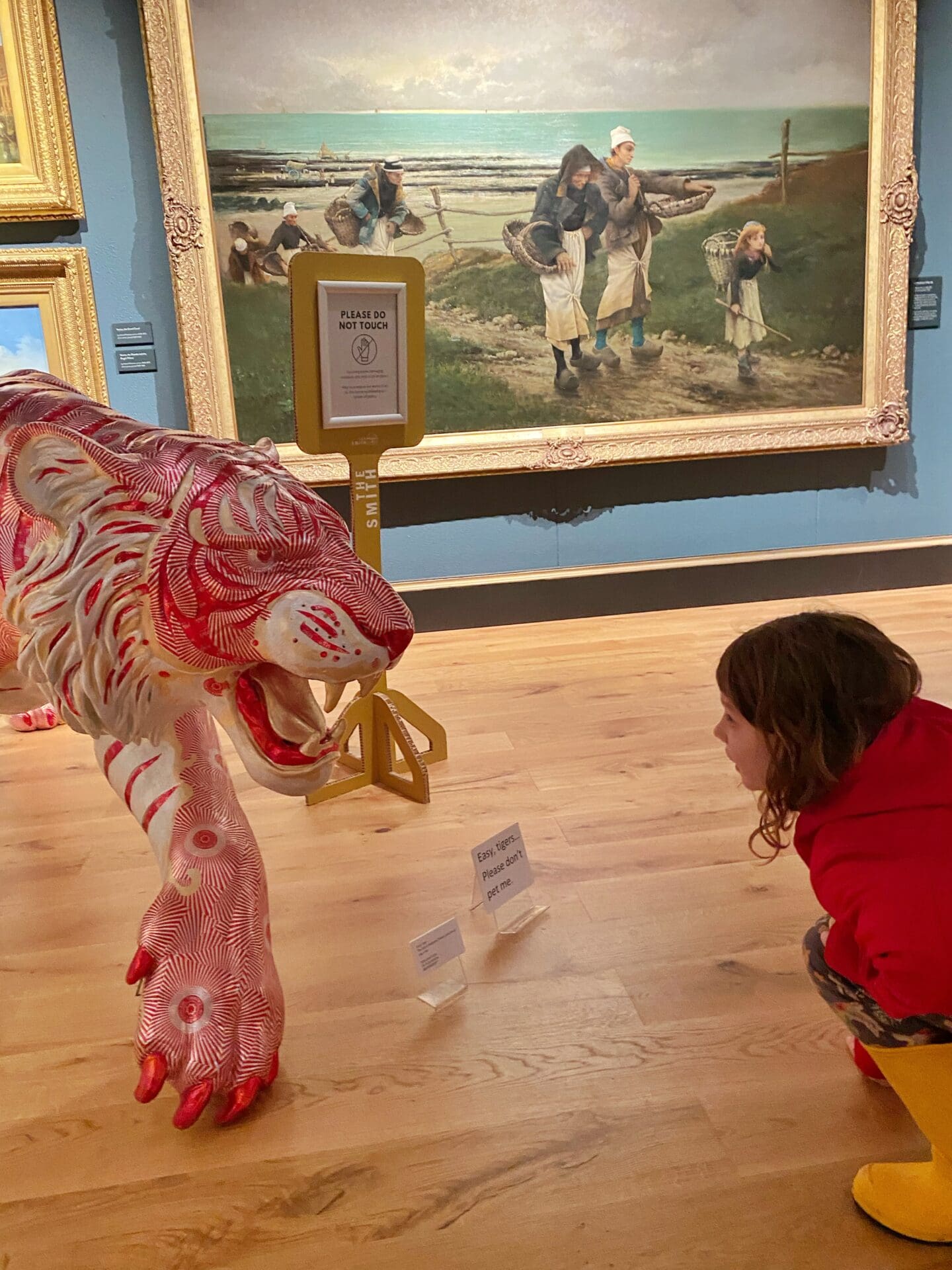 Child looking at sweet wrapper tiger sculpture