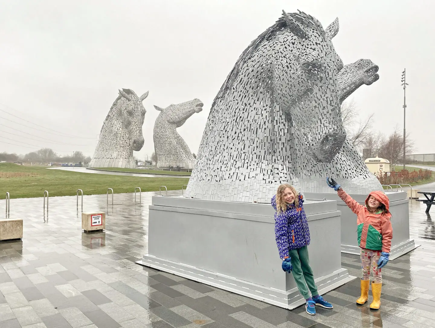 2 children beside miniature Kelpie models with large Kelpies in the background 