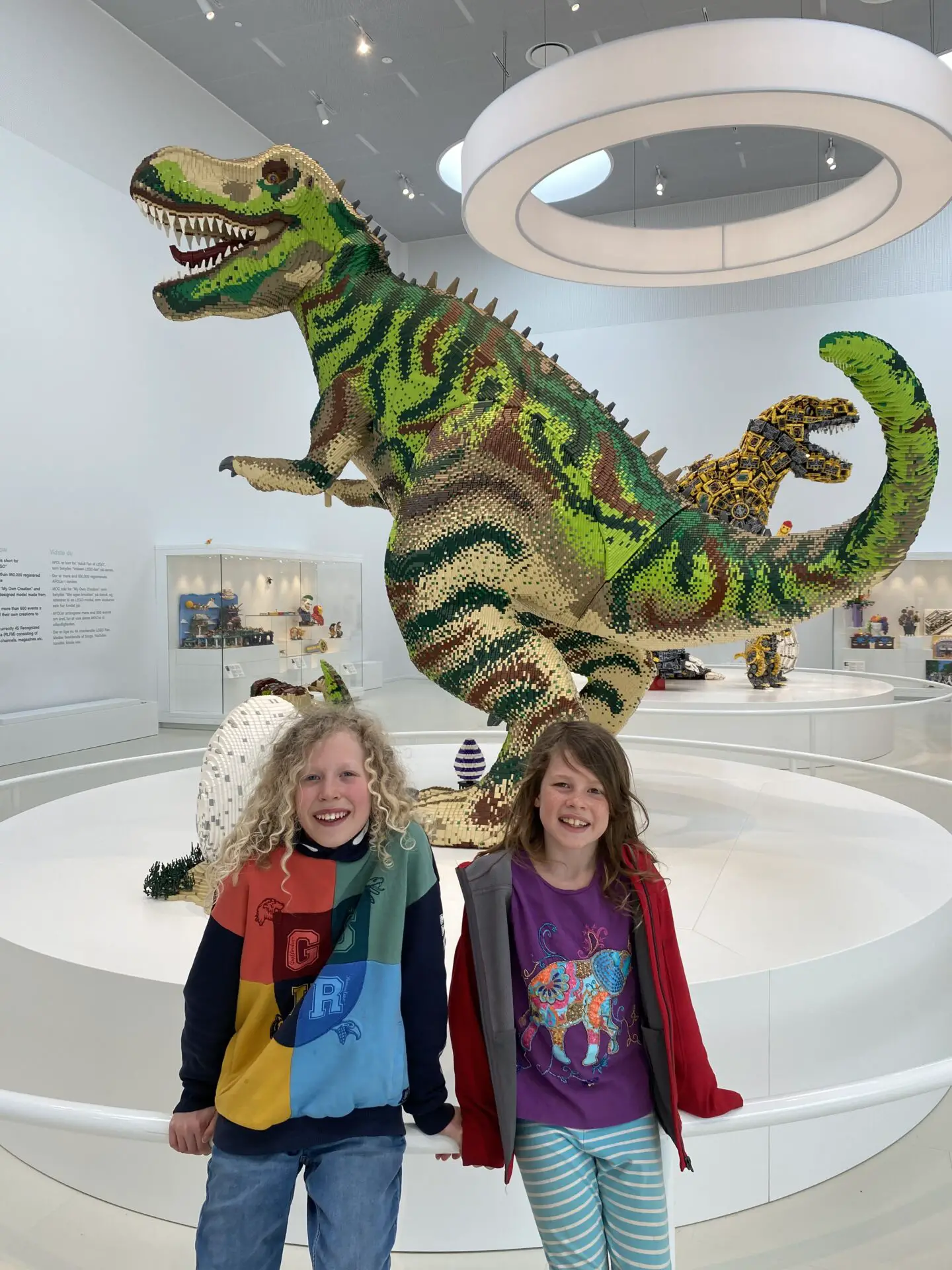 Children standing beside a giant Lego dinosaur