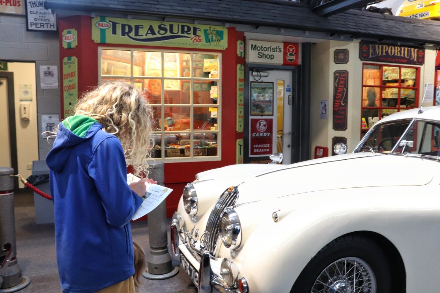 Child writing quiz answers in a vintage motor museum