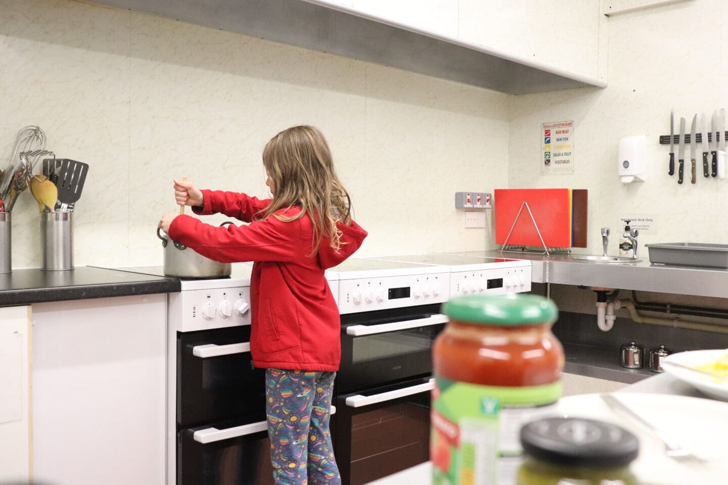 Child cooking pasta at a youth hostel