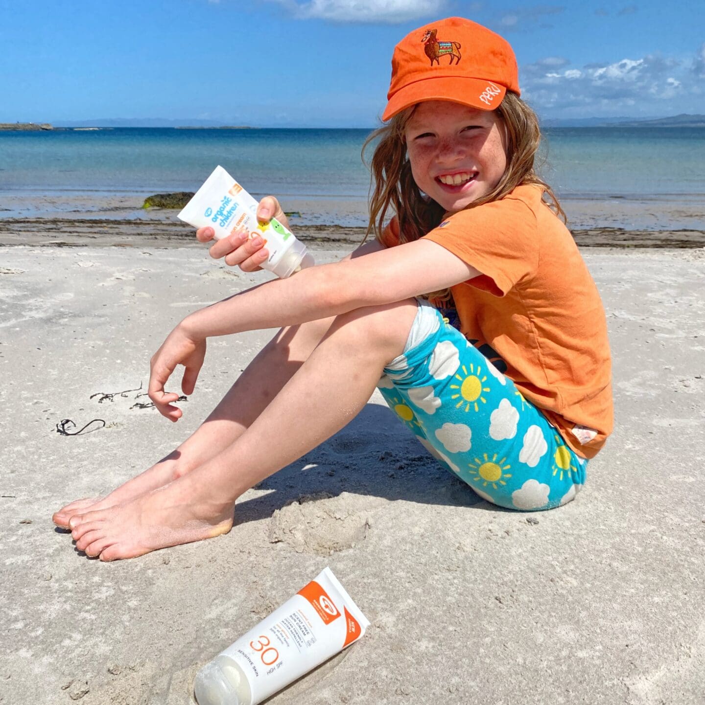 Child on beach applying suncream