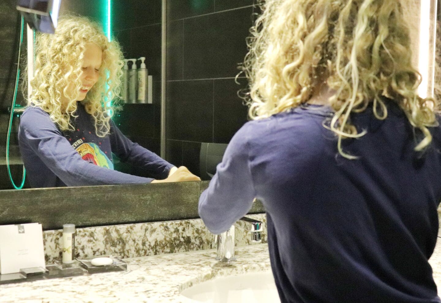 Child washing hands in bathroom