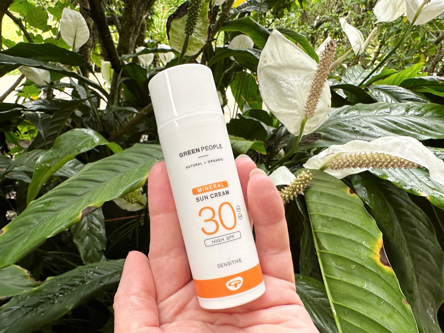Mineral sun cream from Green People beside tropical vegetation